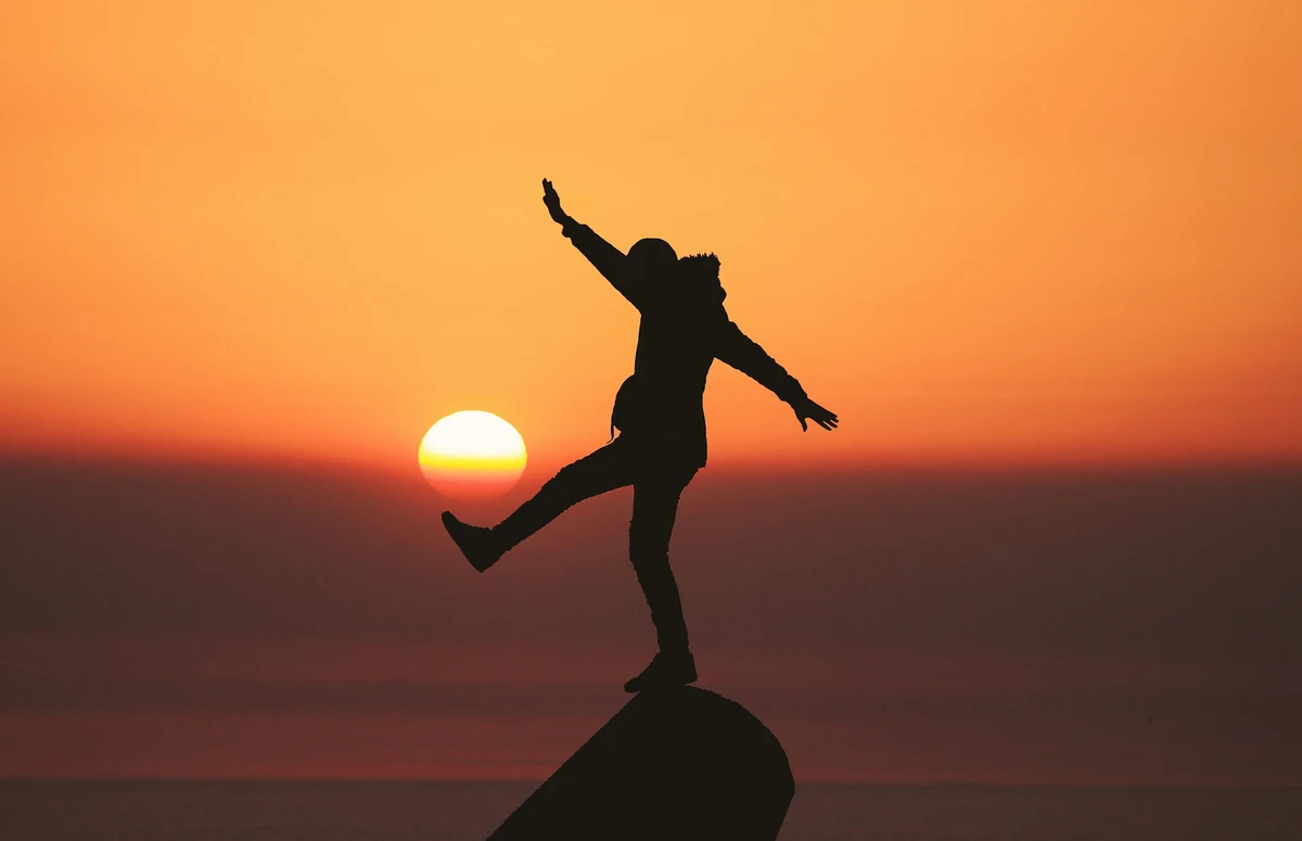 Person celebrating at sunset symbolizing financial peace with life insurance