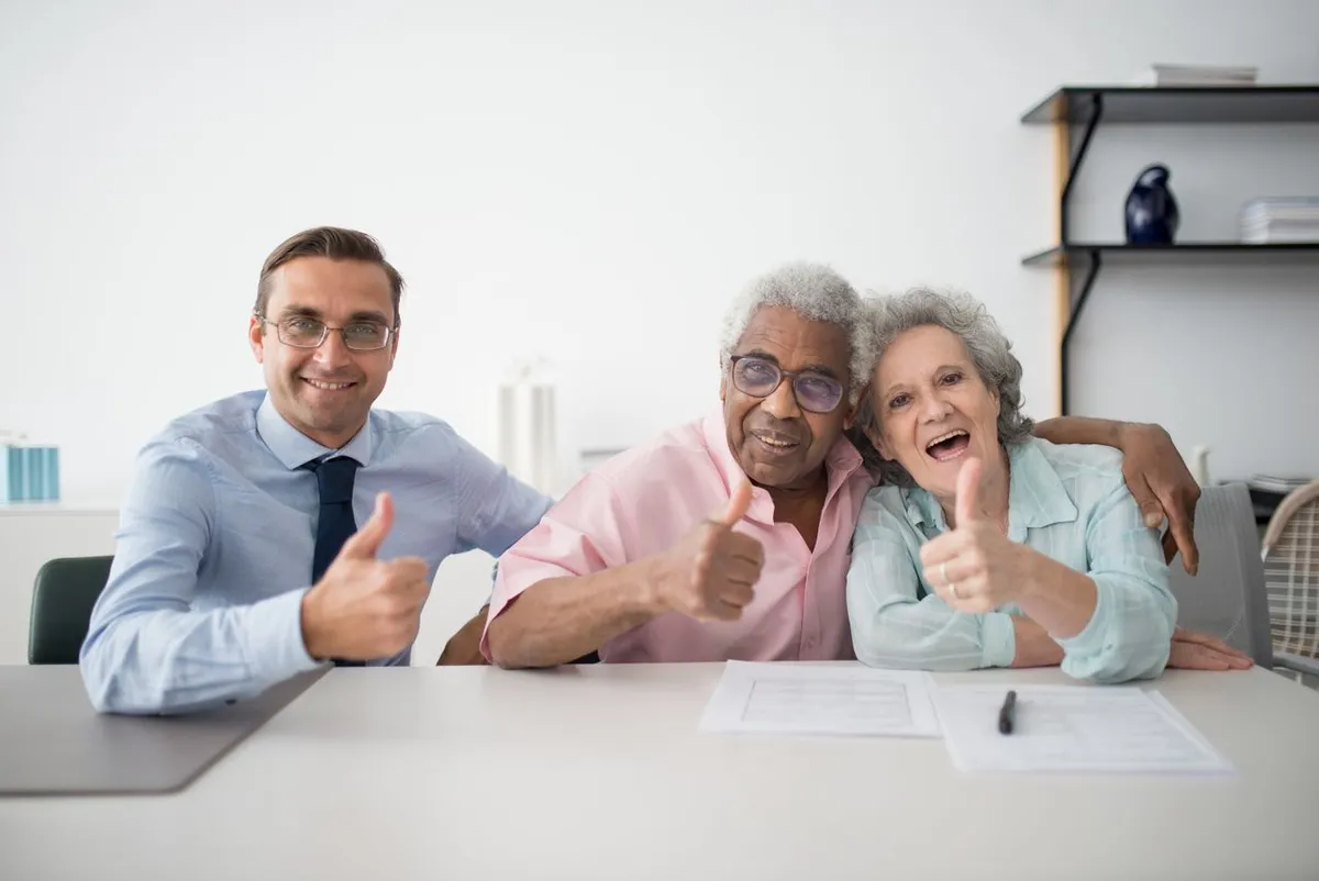 Happy senior couple giving thumbs up with financial advisor representing secure retirement planning