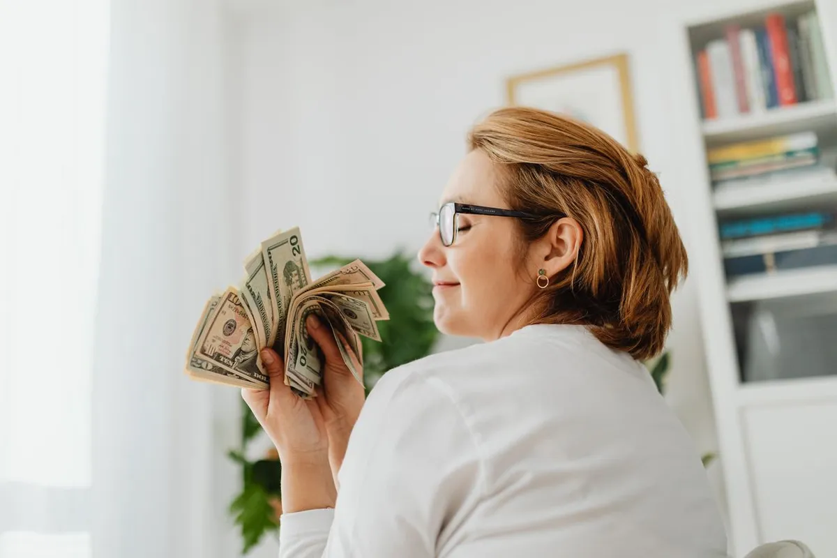 A woman holding a stack of cash representing financial success and multiple income streams
