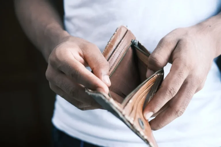 A person holding open an empty leather wallet representing credit score issues and financial struggles