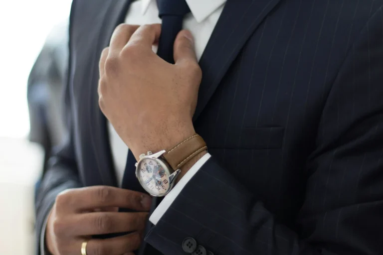 A well dressed man in a suit adjusting his sleeve and luxury watch representing wealth and success