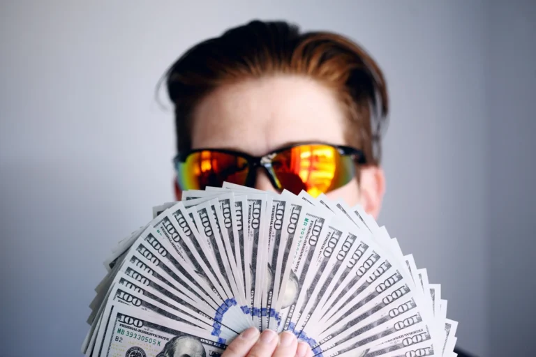 A person holding a fan of US dollar bills representing effective money management and financial success