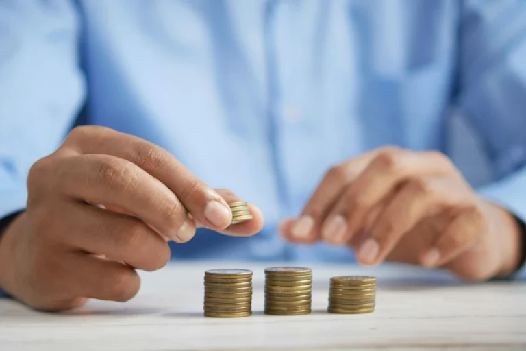 A person stacking coins on a desk representing budgeting for beginners and financial planning