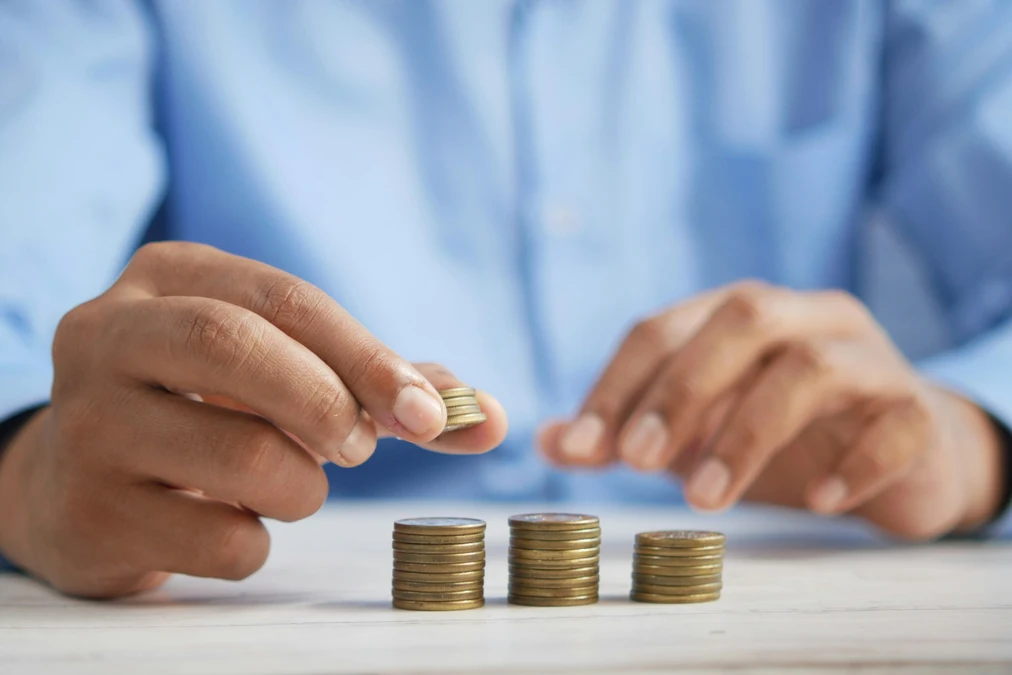 A person stacking coins on a desk representing budgeting for beginners and financial planning