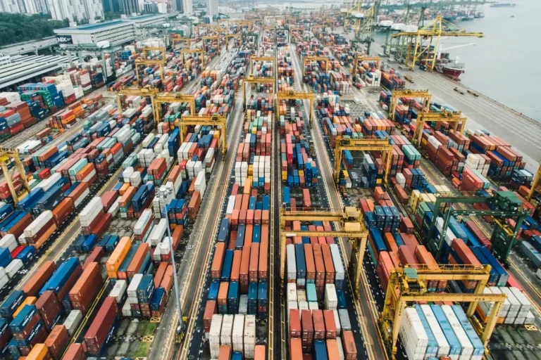 Aerial view of a commercial shipping port displaying rows of colorful cargo containers and heavy lifting cranes, illustrating What Is Trade