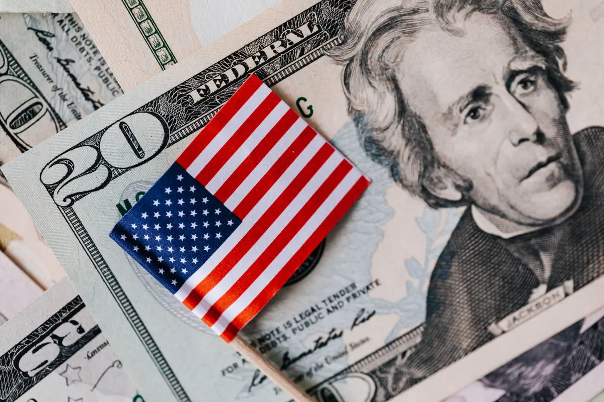 Stack of US dollar bills and a small US flag, representing What Is Monetary Policy