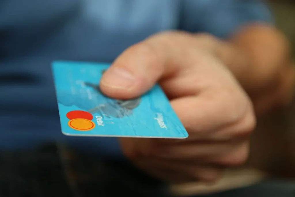 A person holding a blue Debit card represents What Is a Debit Card