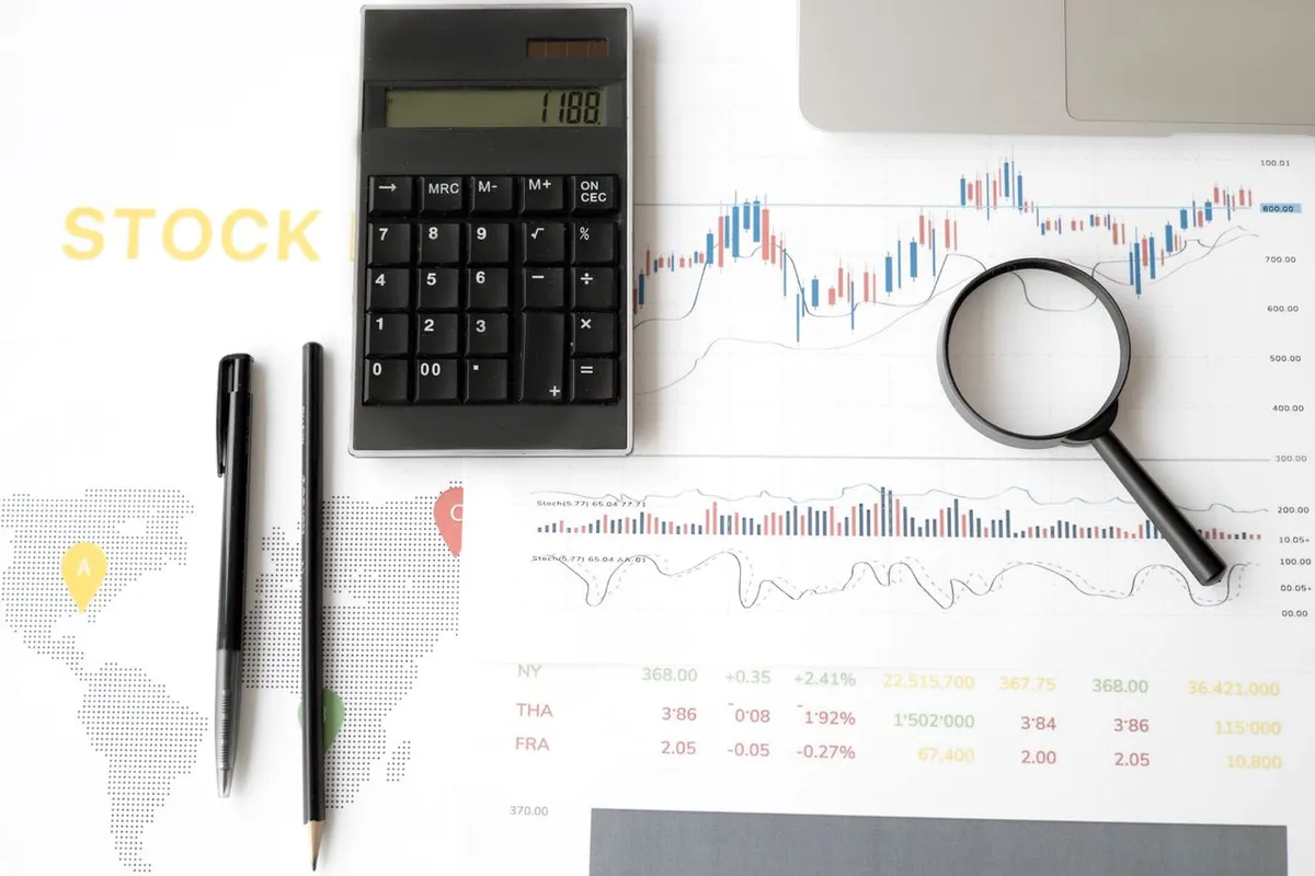 How Interest Rates Affect Stock Markets – Financial charts with a calculator and magnifying glass