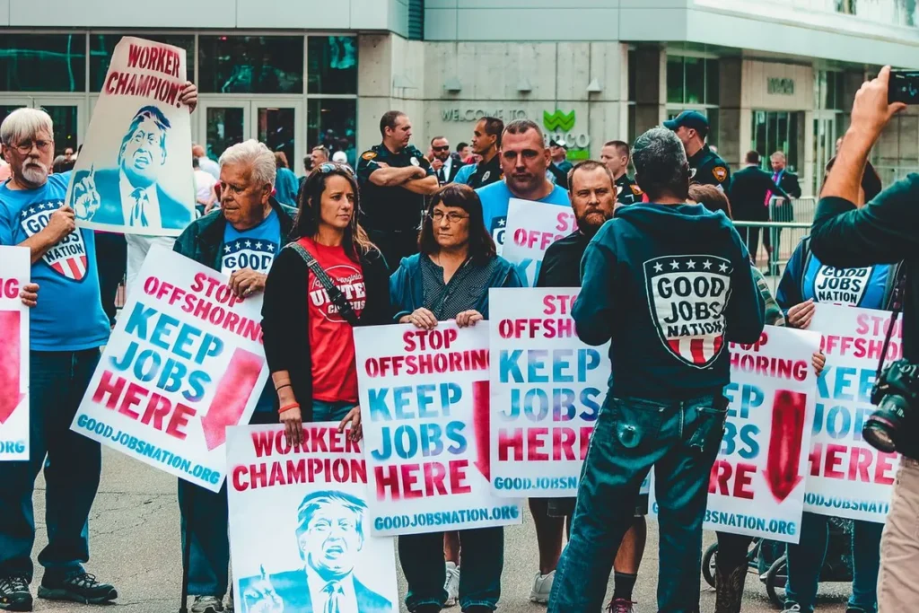 A diverse crowd holding signs at a community protest during US labor market shifts
