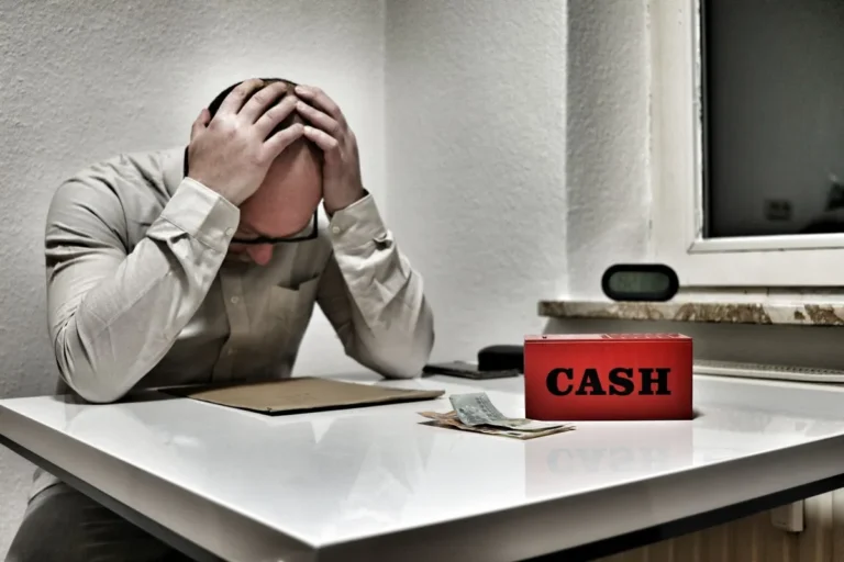 A stressed business owner holding their head in frustration while looking at financial documents, illustrating How to Face a Lack of Customer Demand.