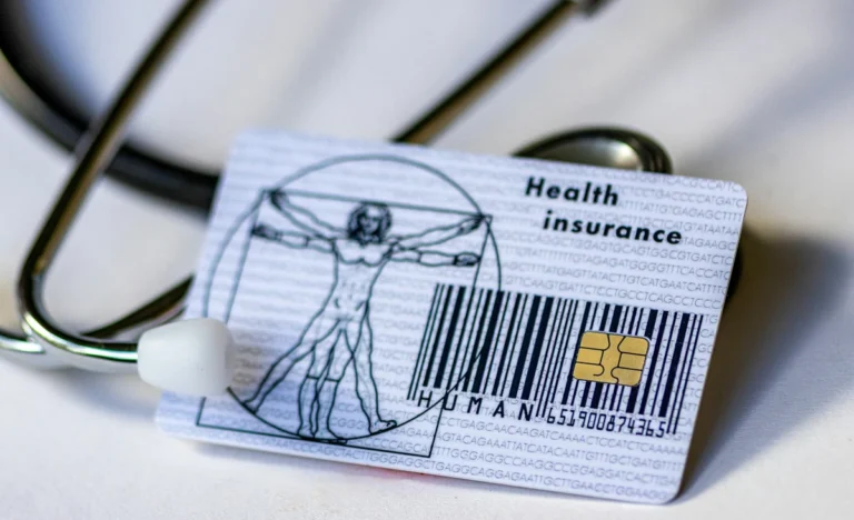 Health insurance card lying on top of medical documents with a stethoscope, illustrating How Does Health Insurance Work in the USA?