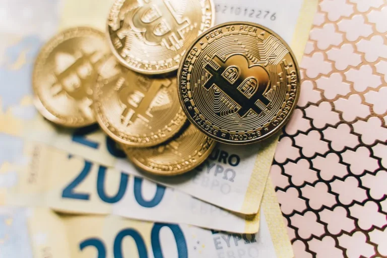 What Is Cryptocurrency? Physical cryptocurrency coins including Bitcoin resting on top of US dollar banknotes.