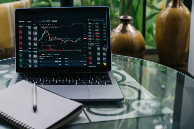 Smart Investing in a High Rate Environment: A laptop displaying trading charts and financial data next to a cup of coffee on a desk.
