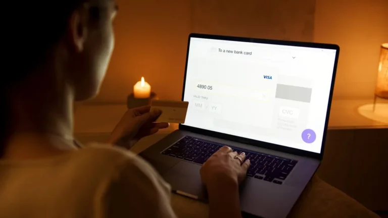 What Is Skrill? - A laptop displaying a digital payment platform on its screen next to a lit candle.