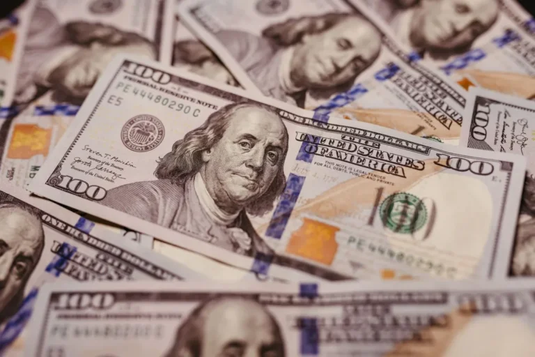 Future Economic Trends to Watch: US dollar banknotes spread out on a wooden surface representing global economic and financial changes.