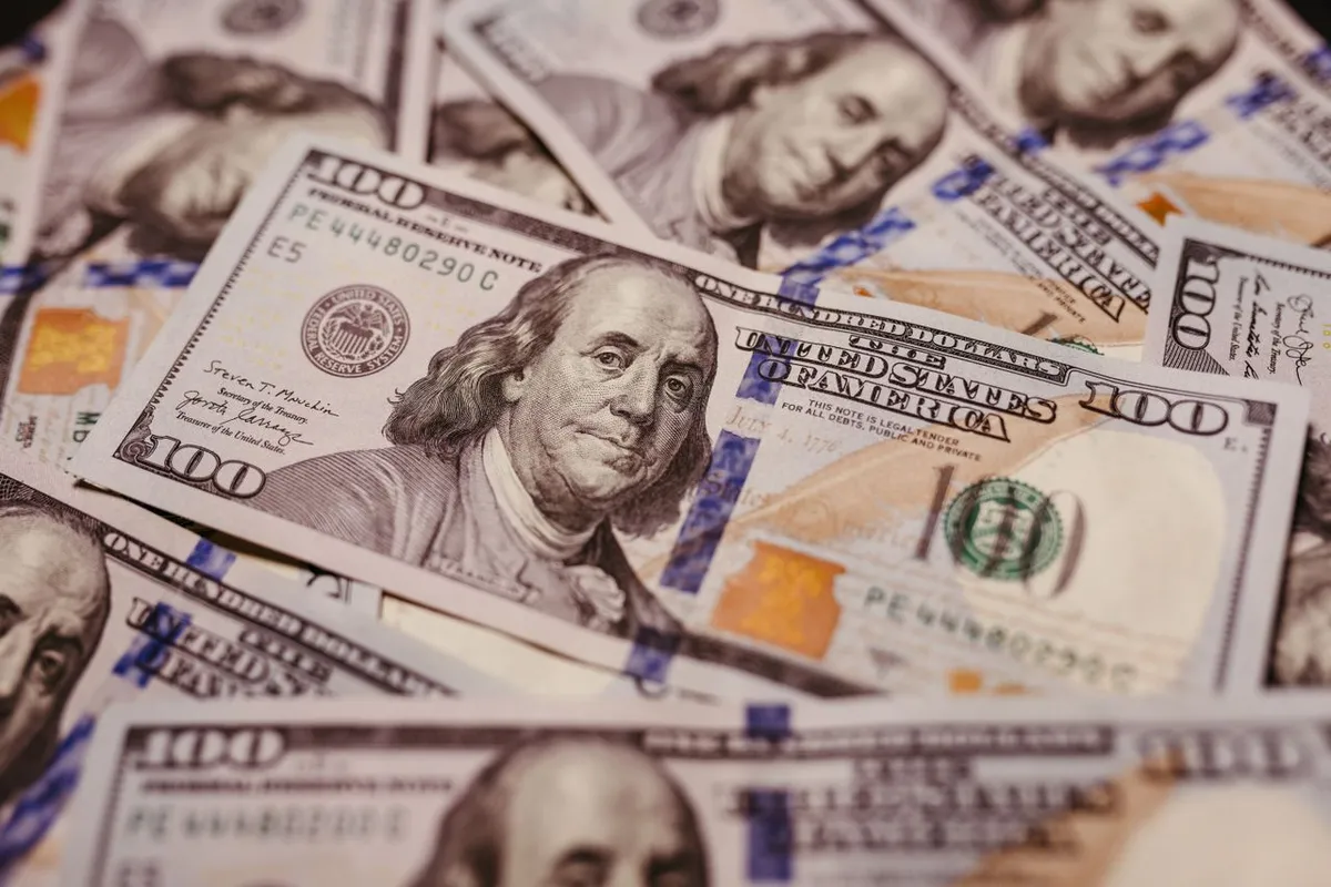 Future Economic Trends to Watch: US dollar banknotes spread out on a wooden surface representing global economic and financial changes.