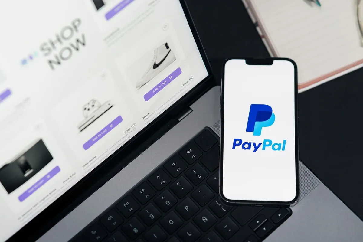 Here is the alt text for your selected featured image: What Is PayPal? A smartphone displaying the PayPal app and a laptop computer on a desk, representing digital payments and online financial services.