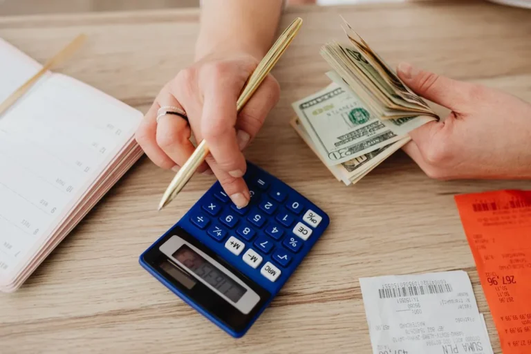 What Is Personal Finance? Hands managing personal finances with cash, a calculator, and financial notes on a desk.