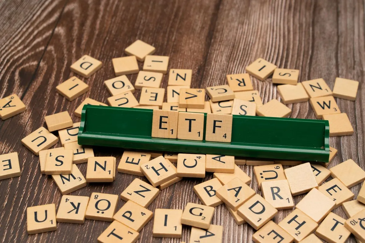 ETF scrabble tiles arranged on a wooden background, representing exchange-traded funds and portfolio strategies for the article Best ETFs During a Recession.